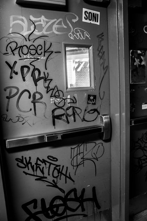 Grayscale Photo of a Door with Graffiti