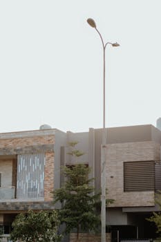 A modern house facade with stone accents and a streetlight in daylight, showcasing contemporary architecture.