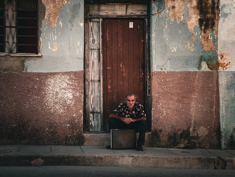 A Man Sitting At A Door