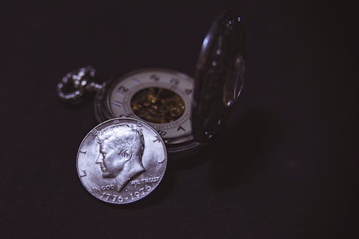 Close-up of a vintage silver coin with a pocket watch, symbolizing time and wealth.