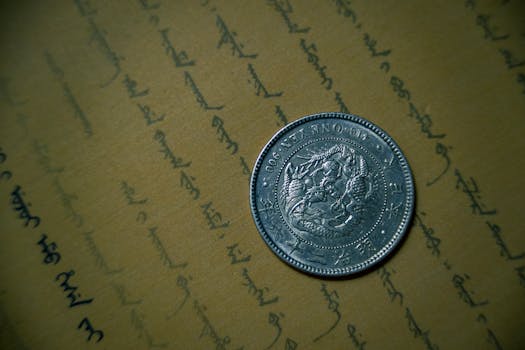 Close-up of an antique silver coin resting on vintage handwritten document.