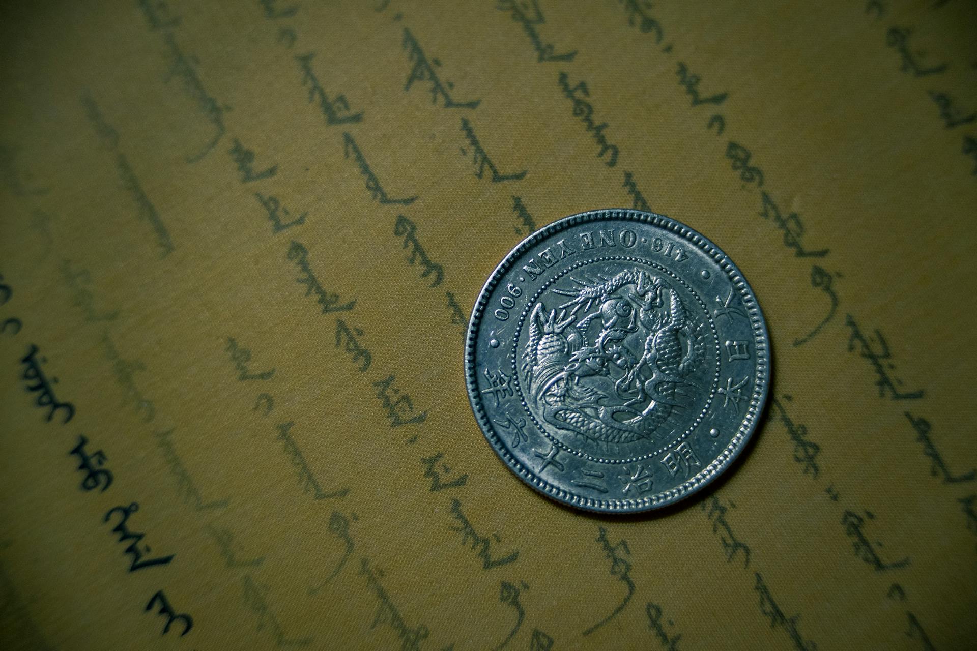 Round Silver-colored Coin on Brown Printer Paper