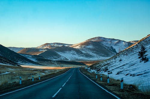 Free Gray Asphalt Road Between Snow Covered Mountains Stock Photo