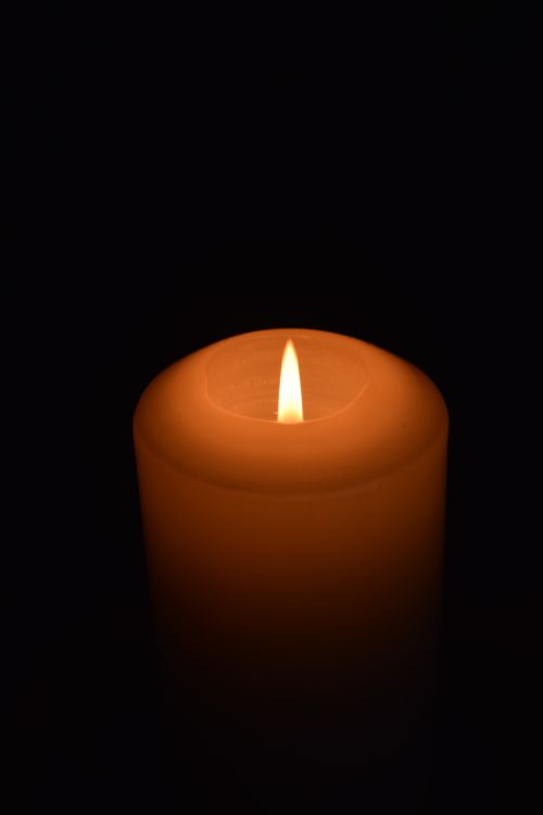 Free Close-up of a candle with a bright flame, creating a serene atmosphere in darkness. Stock Photo