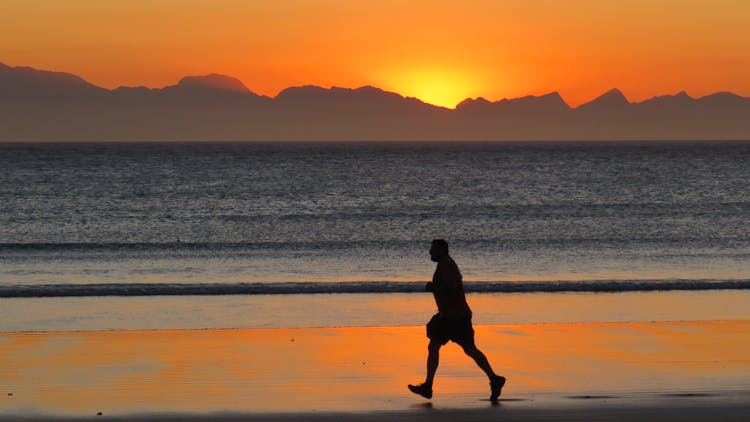 Silhouette Of Man Running On The Beach