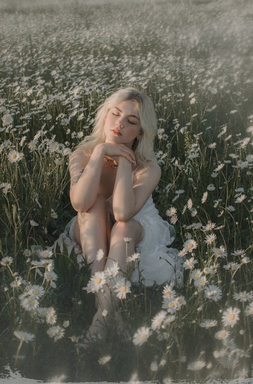 A Woman in White Dress Sitting on Flower Field