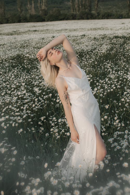 A Woman in White Dress Standing on the Flower Field