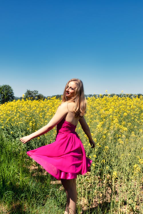 Woman in Pink Dress Standing on a Yellow Flower Field