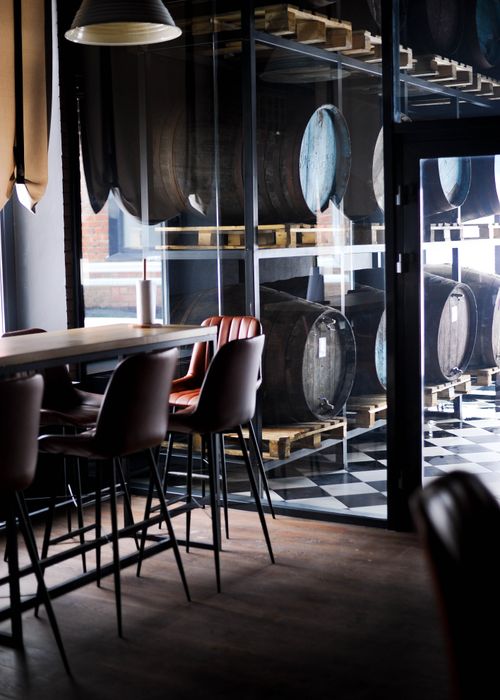 Free Stylish bar interior featuring industrial design elements and stacked barrels in a modern setting. Stock Photo