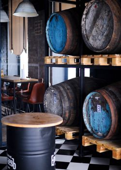 Stylish restaurant interior featuring rustic barrels and industrial decor elements on checkered flooring.