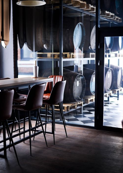 Free Elegant brewery interior featuring wooden barrels and modern seating arrangement for a warm ambiance. Stock Photo
