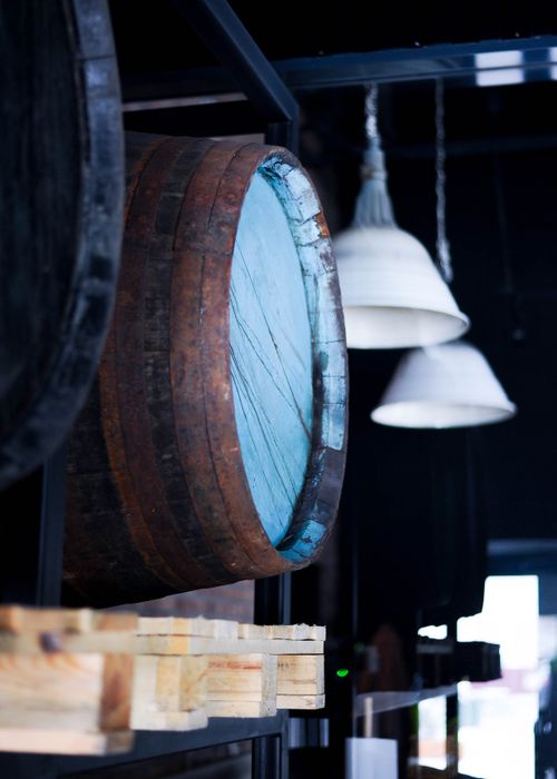 Free Close-up of a rustic wooden barrel in an industrial indoor setting with hanging lamps. Stock Photo