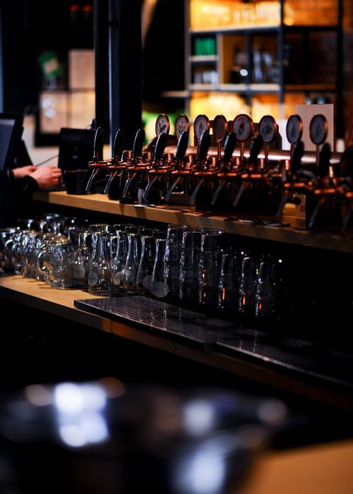 Free Beer taps lined up at a modern bar with glasses. Warm, inviting ambiance with low lighting. Stock Photo
