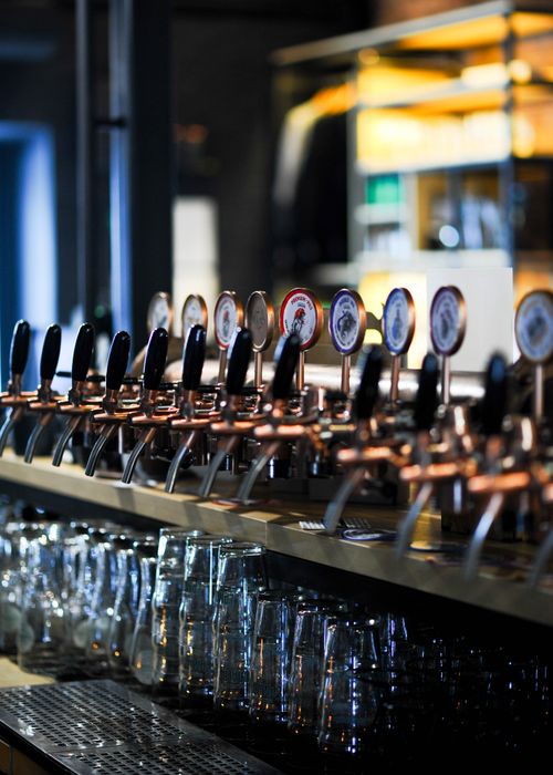 Free Vertical shot of multiple beer taps with glasses in a cozy bar setting, perfect for hospitality themes. Stock Photo