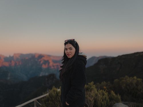 Free A woman in a coat stands in the mountains at sunset, capturing serene beauty. Stock Photo
