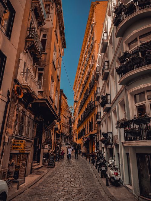 Free Scenic view of a narrow cobblestone street lined with historic buildings in a vibrant old town. Stock Photo