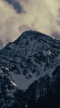Dramatic snow-capped mountain under a cloudy sky in Эстосадок, Russia.
