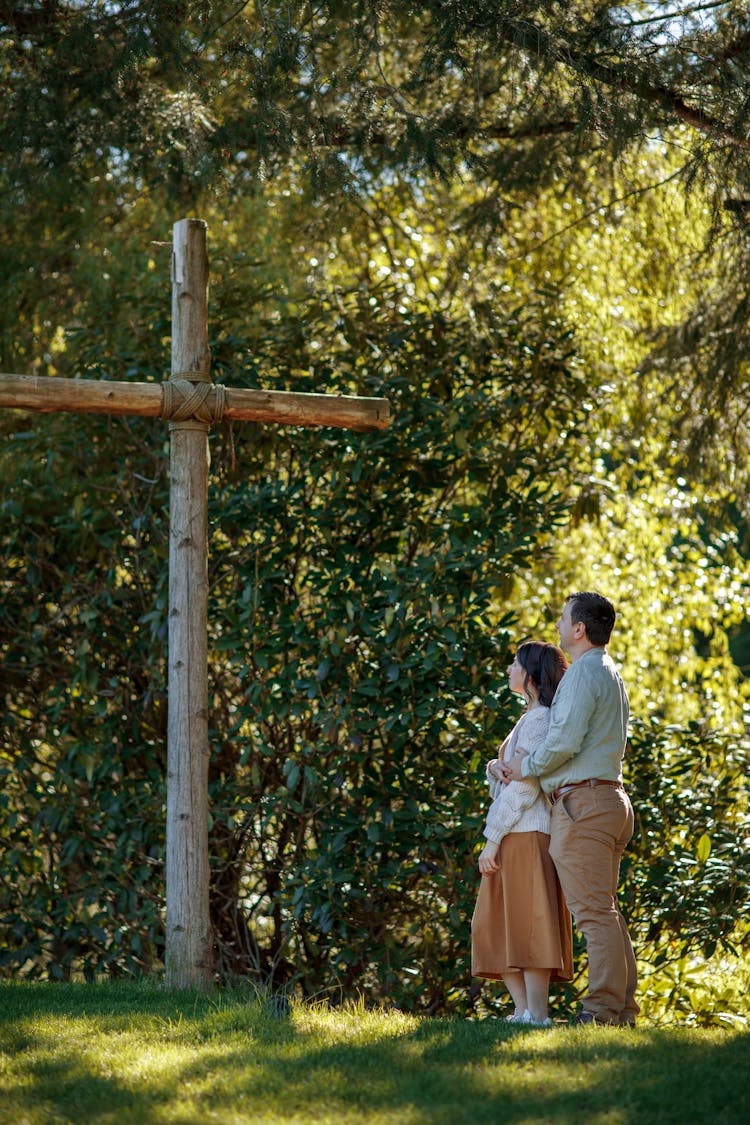 Woman And Man Praying By Cross