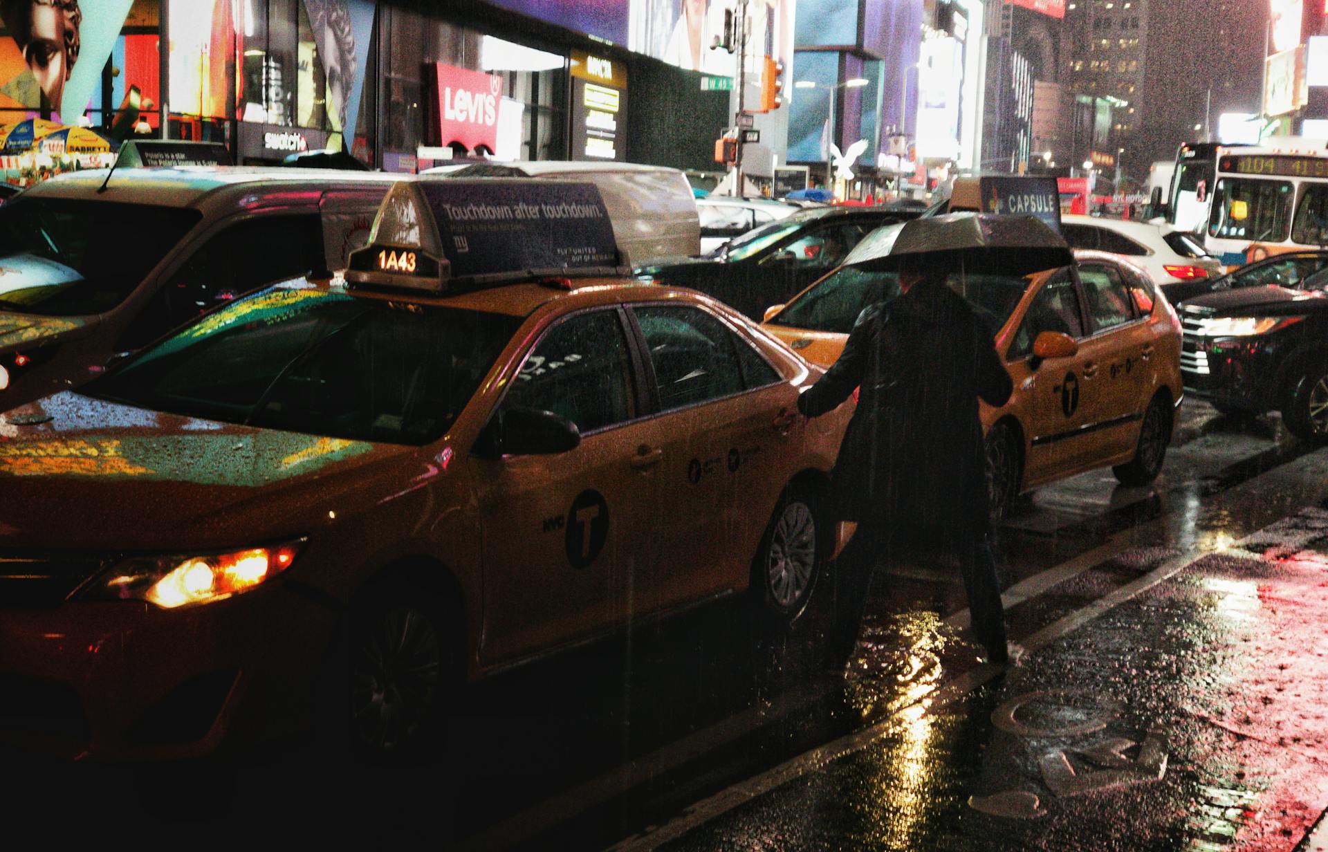 New York City taxis in Times Square on a rainy night, reflecting urban hustle.