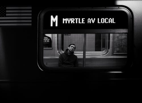 Grayscale Photo of Man Sitting Inside the Train