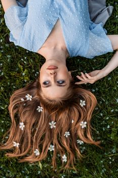 Woman in Blue and White Polka Dot Shirt Lying on Green Grass