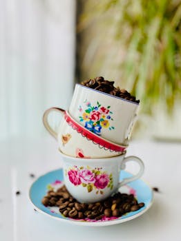 A close-up of floral ceramic cups stacked with coffee beans, offering a cozy and vibrant feel.