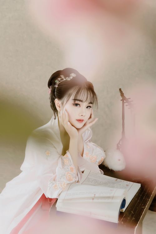 Free A serene portrait of a young woman in traditional clothing reading a book indoors. Stock Photo