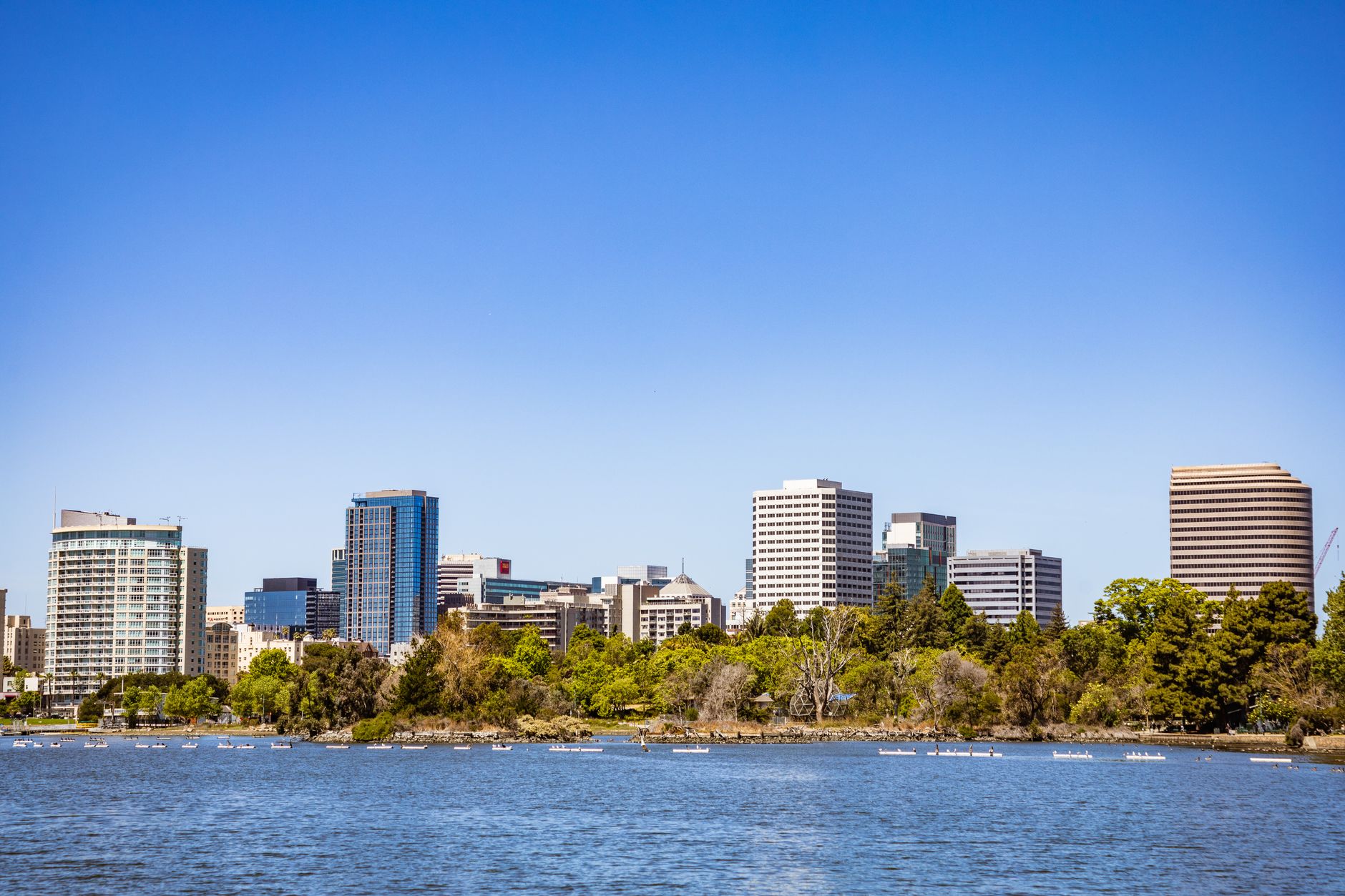 City skyline featuring modern office buildings and a riverfront view under a clear blue sky.