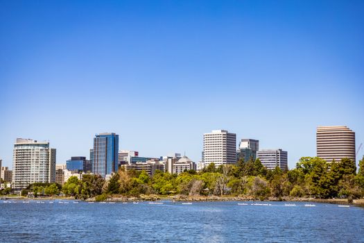 City skyline featuring modern office buildings and a riverfront view under a clear blue sky.
