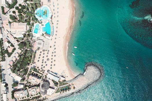 A stunning aerial view of a tropical beach, resort, and clear blue sea.