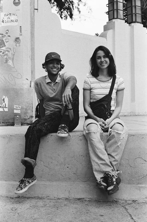 Young Man and Woman Sitting on the Concrete Bench 