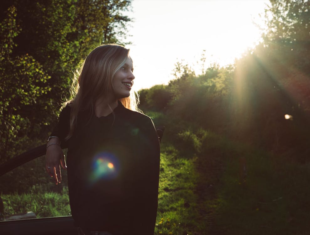 Free Woman Leaning on Car Door Under Sunny Sky Stock Photo