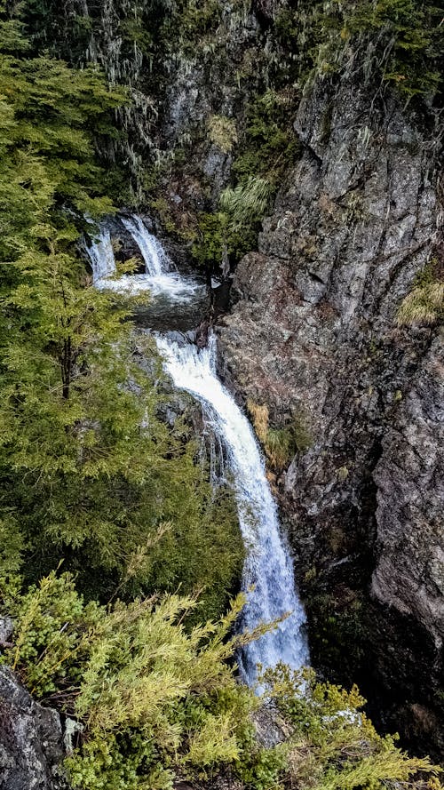 Water Falls Between Brown and Green Rock Formation