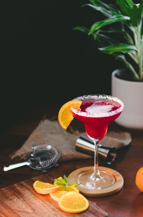 Shot of a Pink Cocktail and Orange Slices on Bar Table