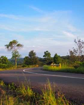 Beautiful countryside road in West Java, Indonesia, surrounded by lush greenery and clear skies, offering a serene nature view.