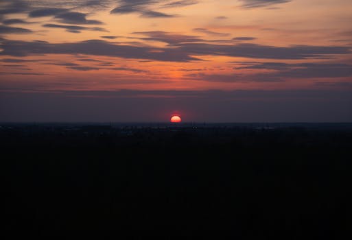 A beautiful sunset casting warm hues over the horizon, featuring a dramatic sky with scattered clouds.