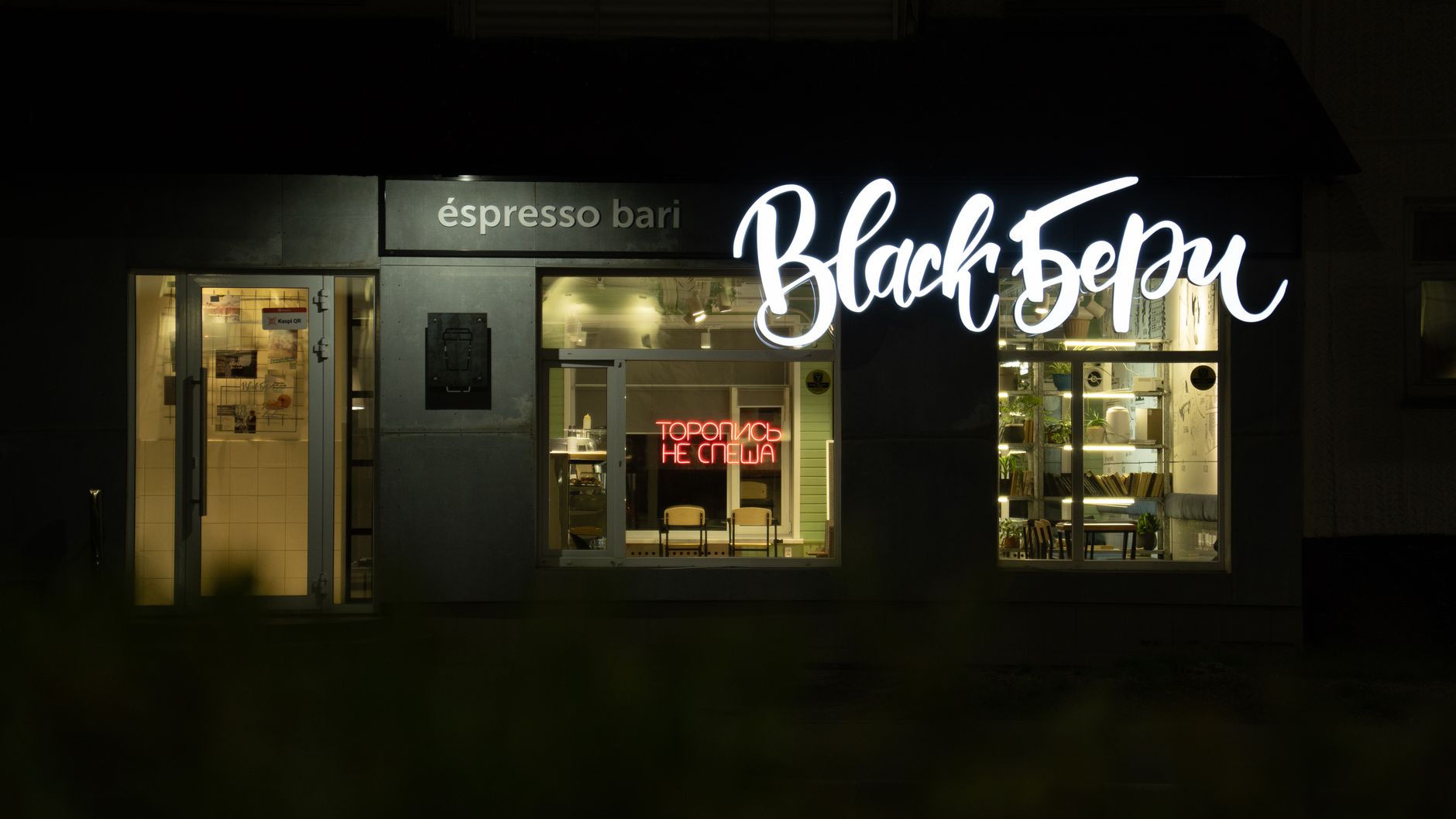 A cozy café with bright neon and script signage, captured during a tranquil night.