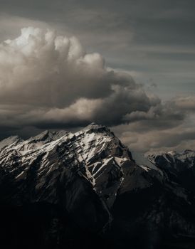 Majestic view of snowcapped mountains under looming clouds in Alberta, Canada. Perfect for nature enthusiasts.