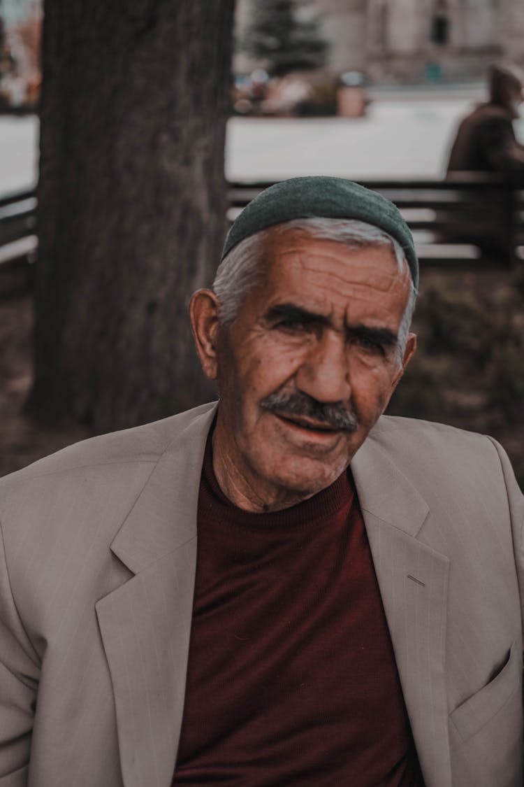 Old Man With Traditional Headwear Sitting In Park