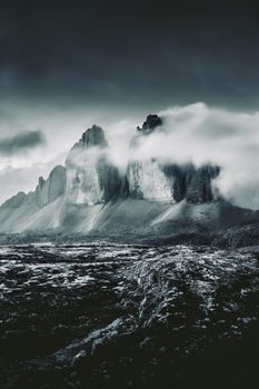 Dramatic mountain peaks shrouded in misty clouds during a moody twilight scene.