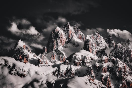 A breathtaking view of a snow-covered mountain range under a dramatic night sky, showcasing winter scenery.