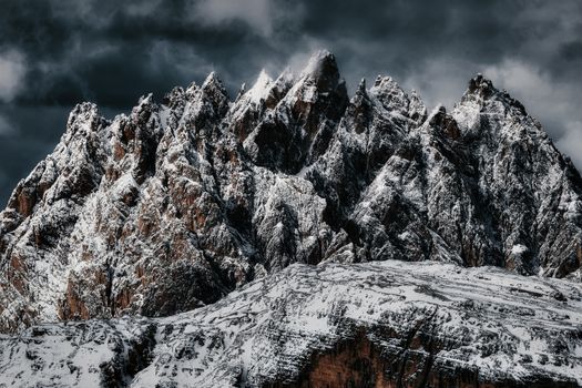 A stunning view of rugged, snow-covered mountain peaks under a dramatic cloudy sky.