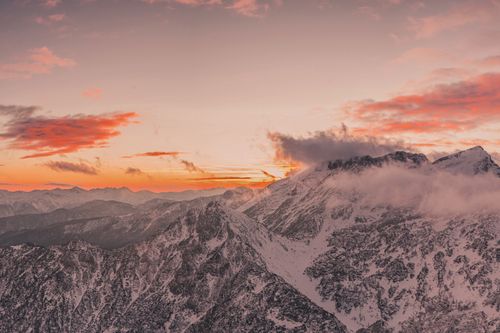 Free Breathtaking aerial view of snow-covered mountains during a vibrant winter sunset. Stock Photo