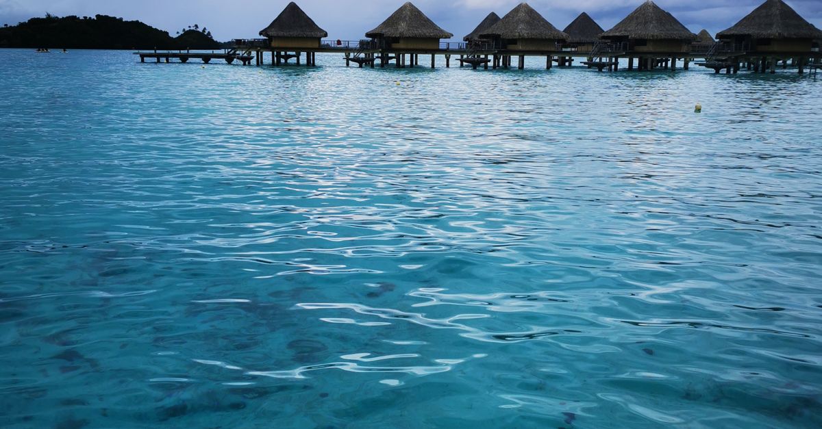 Scenic view of overwater bungalows in Bora Bora with turquoise water and cloudy skies.