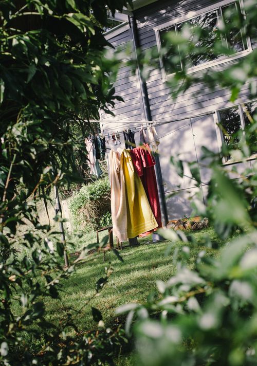 Free Vibrant clothes drying on a line in a sunny backyard surrounded by lush greenery. Stock Photo