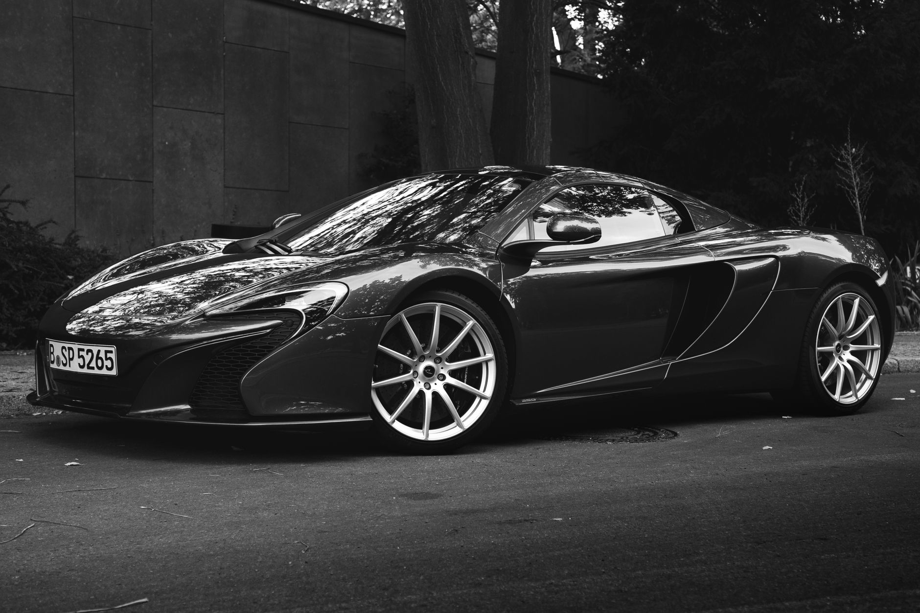 Grayscale image of a sleek McLaren supercar parked outdoors in Berlin, Germany.