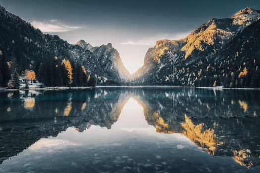 Breathtaking view of a mountain lake reflecting the surrounding peaks and fall foliage, creating a serene and picturesque landscape.