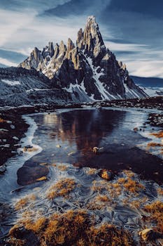 Stunning winter landscape with snow-capped mountains and an icy lake reflecting their grandeur.