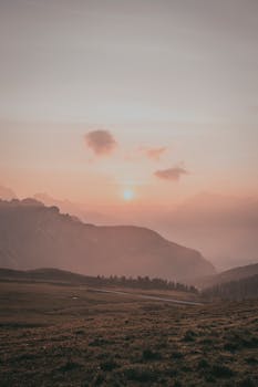 Capture of a serene sunrise casting warm hues over a foggy mountain landscape.