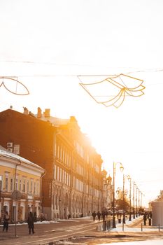 Beautiful city street at sunset with winter decorations and historic architecture.
